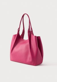 Różowa torba na ramię z miękkiej skóry o ziarnistej fakturze, szerokim otwarciu i dwoma wydłużonymi uchwytami. Charakteryzuje się miękkim, niestandardowym kształtem.