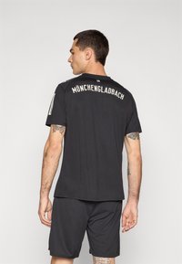 Svart sporttröja och shorts i lättviktsmaterial. Tröjan har texten "MÖNCHENGLADBACH" på ryggen, med korta ärmar och rund hals.