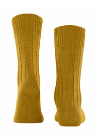 Calze giallo senape con un design a coste e una superficie liscia, alte fino al polpaccio, con orli e punte rinforzati.