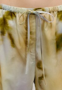 Lichte, pastelgekleurde broek met een strikdetail aan de voorkant, met een vloeiend patroon in groene en beige tinten en een elastische tailleband.