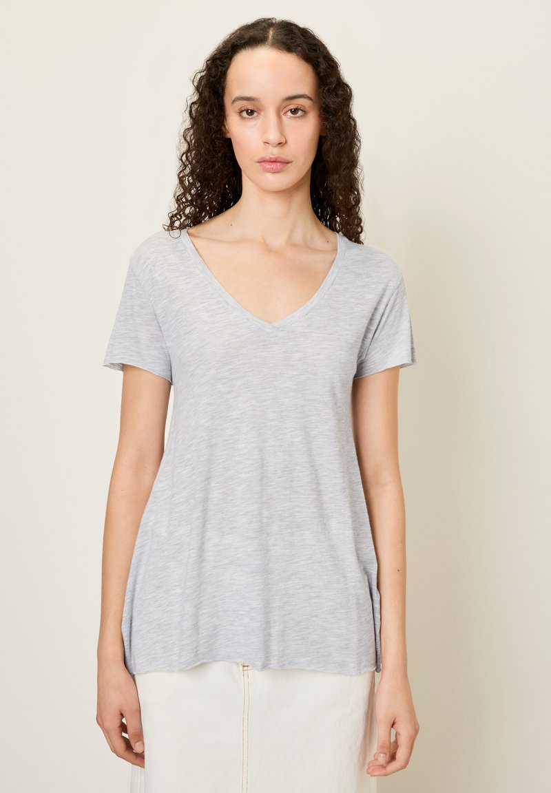 Pilkas, trumpas rankovėmis V-nesmuklis marškinėliai, pagaminti iš minkštos, lengvos medžiagos, su atsipalaidavusiu siluetu ir apvaliu sijonu, pasižymintys subtiliais tekstūros pokyčiais.