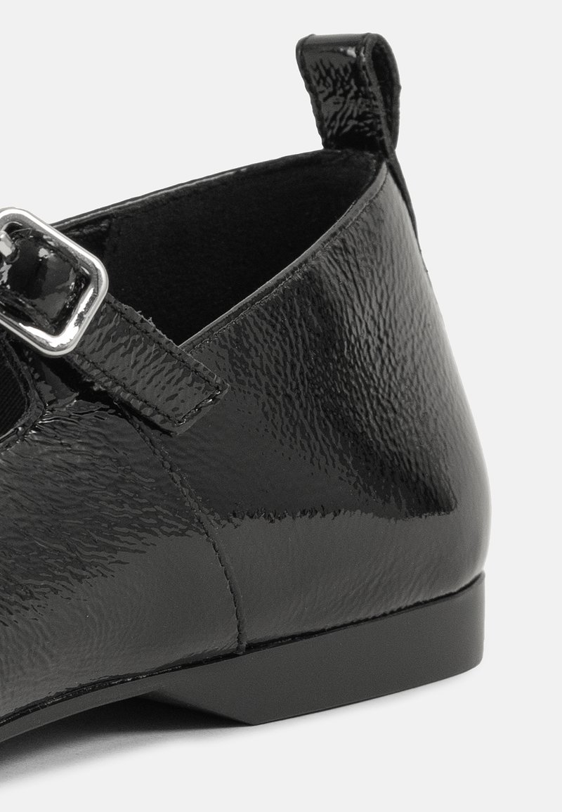 Chaussure en cuir verni noir avec une finition texturée, dotée d'une boucle en argent et d'un talon bas. Conçue avec un orteil arrondi et un soutien de la cheville.