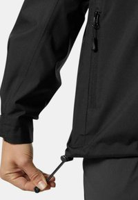 Chaqueta negra con una textura suave y mate, cordón ajustable en el dobladillo y un bolsillo con cremallera en el lateral.