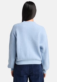 Maglione a coste azzurro chiaro con vestibilità comoda, spalle scese e colletto rotondo. Abbinato a pantaloni in velluto a coste blu navy.
