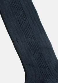Calcetines hasta la rodilla de color azul marino oscuro con canalé texturizado vertical, que presentan patrones sutiles de ondas y un acabado de tela suave y lisa.