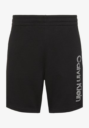 Fekete sportnadrág elasztikus derékrésszel, jobb lábszáron függőlegesen nyomtatott "Calvin Klein" logóval.
