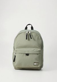 Sac à dos en tissu vert clair de forme arrondie, fermeture à double zip, poche avant, et petite étiquette logo en bas à droite.