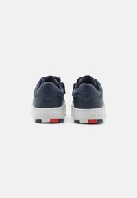 Sneakers in pelle blu navy con suole bianche. Le caratteristiche includono un design testurizzato e accenti del logo in rosso e blu sul tallone.
