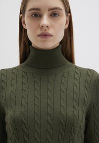 Olivgrüner Kabelstrick-Rollkragenpullover mit geripptem Kragen und strukturiertem Muster, aus weichem, dehnbarem Stoff gefertigt.