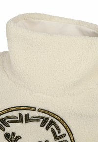 Fleece-Pullover in Creme, mit hohem Kragen und schwarzem gesticktem kreisförmigem Design. Weiche Textur mit gestickten Details.