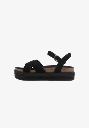 Sandali platform neri con fasce incrociate, cinturino alla caviglia regolabile e suola in sughero. Suola esterna nera testurizzata con design intrecciato.