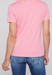 Rosa kortärmad t-shirt med rund halsringning, tillverkad av lättviktig tyg, kombinerad med blå denimjeans med en klassisk femficksdesign.