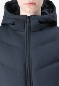 Navy puffer jacket with a high collar and hood. Features a central zipper and chevron quilted pattern. Smooth, matte texture.
