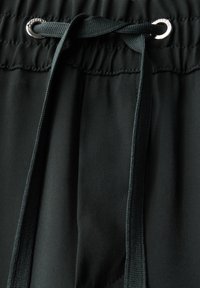 Svart idrottsshorts med snörning, med en sl ät tygtextur, metallöglor och elastisk midja.