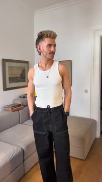 White ribbed tank top paired with black wide-leg pants featuring a drawstring waist; subtle stitching details; casual home setting.