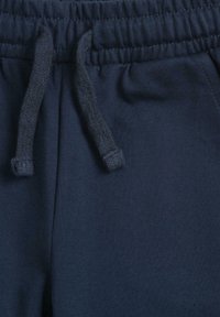 Pantalon bleu marine avec cordon de serrage, taille texturée et couture plate. Comprend des cordons tressés pour un ajustement réglable.