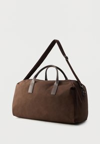 Καφέ υφασμάτινη τσάντα duffel με δερμάτινες λεπτομέρειες, διαθέτει διπλές λαβές και αποσπώμενο ιμάντα ώμου. Λεπτή υφή με κομψό σχεδιασμό.