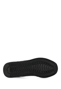 Černá podrážka boty s hlubokým, drážkovaným vzorem navrženým pro trakci a odolnost, vyfotografována zespodu na bílém pozadí.