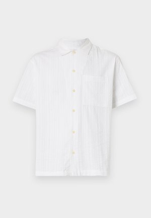 Camisa branca de manga curta com fecho de botão, apresentando um único bolso, tecido texturizado e botões amarelo-claro.