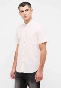 Koszula z krótkim rękawem w jasnym beżowym kolorze, zapinana na guziki, wykonana z fakturowanej tkaniny z ostro zakończonym kołnierzykiem i zaokrąglonym dołem, z jasnymi guzikami.