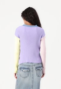 Rebrast pulover s kratkim vijoličastim telesom in dolgimi rokavi v pastelnem barvnem spektru: rumena, roza in modra. Zadnji pogled prikazuje zaobljen izrez.