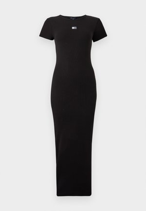 Svarte ribbede maxikjole med kortermet og rund hals. Har en liten logo spenn på brystet. Jevn tekstur gjennom hele kjolen.