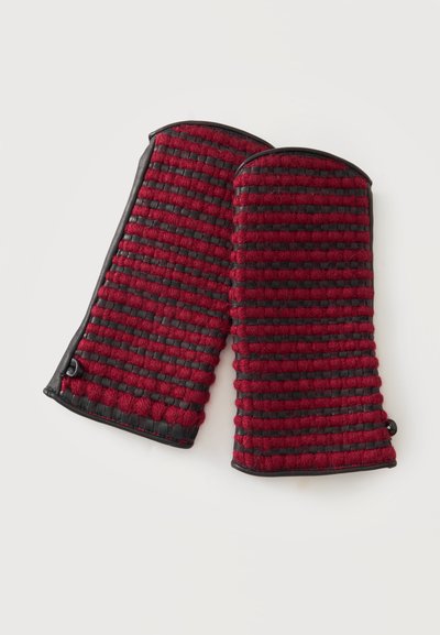 Paire de maniques rouges et noires rayées avec tissu texturé et dessus arrondis sur un fond clair.