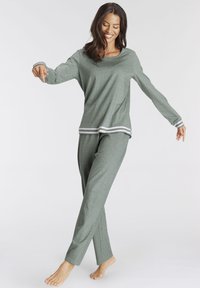 Grünes Baumwoll-Loungewear-Set mit langen Ärmeln und lockeren Hosen. Mit weißen Streifen an den Ärmelbündchen und am Saum. Weiche Textur, entspannter Schnitt.
