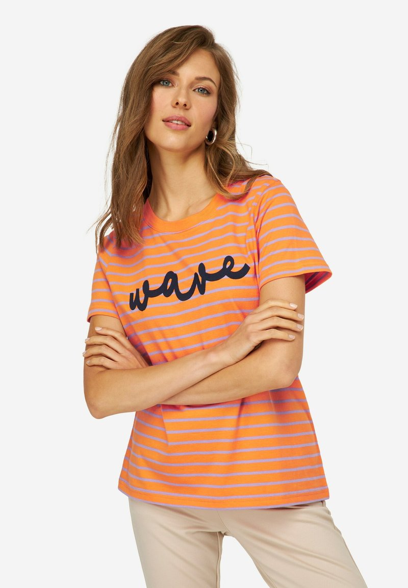 Camiseta de rayas en naranja con rayas moradas claras; presenta texto "wave" en negro. Cuello redondo y mangas cortas. Material de algodón suave.
