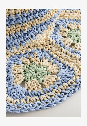 Rund flätad matta med blå, beige och gröna färger samt en texturerad, vävd design. Mönstret innehåller blommotiver och kontrasterande kanter.