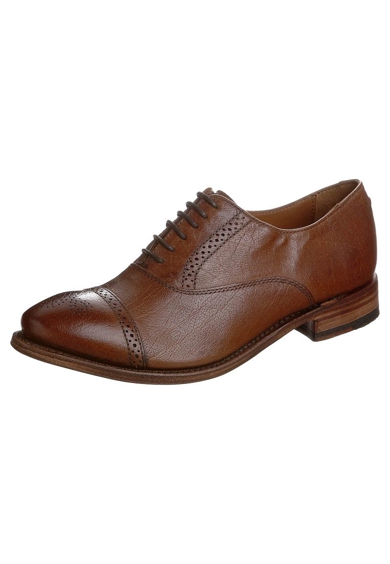 Chaussure en cuir marron à lacets avec un bout arrondi, des perforations brogue détaillées et un petit talon empilé. Texture lisse avec un éclat subtil.