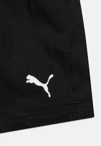 Melni auduma sporta šorti ar gludu tekstūru; kreisās puses vidū ir redzams baltais Puma logo lēciena pozīcijā. Redzami tīri šuvju sīkie elementi.