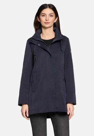 Veste coupe-vent marine en tissu résistant à l'eau, dotée d'une capuche amovible, de boutons croisés et de poches latérales. Texture lisse.