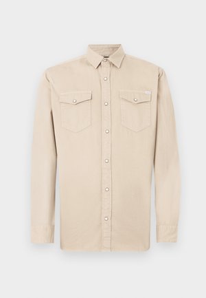 Beige katoenen shirt met lange mouwen en een button-down kraag, voorzien van twee borstzakken en een knoopsluiting aan de voorkant. Zachte textuur.