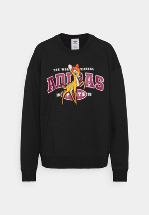 Musta collegepaita, jossa suuri Adidas-logo ja Disneyn Bambin hahmon kuva etupuolella.