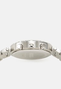 Sølv rustfritt stålur med et rundt hus, tre trykkere på siden og et jevnt metallarmbånddesign. Gravet inn med "BOSS."