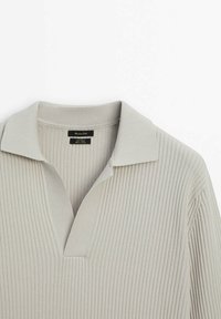 Pull en tricot côtelé gris clair avec un col et une patte de boutonnage partielle. Présente une texture douce et une coupe décontractée.