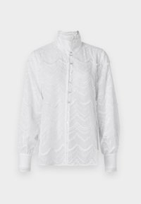 White blouse with a high collar, button-front closure, and textured wavy pattern. Features puffed sleeves and lace trim accents.