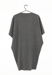 Haut ample à manches courtes gris foncé avec des lignes de couture, suspendu sur un cintre noir contre un fond blanc.