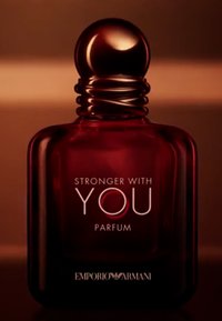 Flacon de parfum en verre rouge avec un col arrondi et strié et un bouchon sphérique lisse. Le texte affiche "STRONGER WITH YOU PARFUM," avec le logo en dessous.