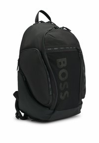 Czarny plecak z gładkiego, matowego materiału i siateczkowymi akcentami. Wyposażony w wiele zamków, regulowane paski i duży logo z przodu.