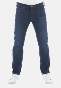 Jeans de mezclilla azul oscuro con corte recto, cinco bolsillos y costuras visibles. Combinados con zapatillas blancas, sobre un fondo claro.