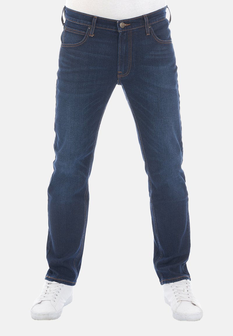 Jeans de mezclilla azul oscuro con corte recto, cinco bolsillos y costuras visibles. Combinados con zapatillas blancas, sobre un fondo claro.