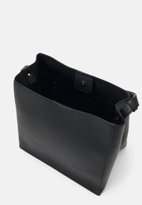 Sac fourre-tout en cuir noir avec une finition texturée, ouverture par le haut, deux poches intérieures et accents en métal doré.