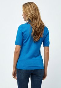 Kortärmad blå stickad tröja med en figurnära design. Slät textur och ribbade detaljer vid ärmarna och nederkanten. Bärs med mörka jeans.