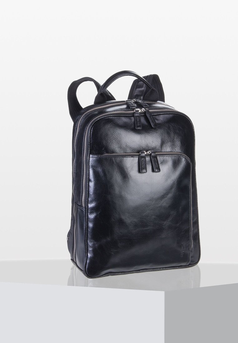 Sac à dos en cuir noir avec compartiments zippés à l'avant et sur le dessus, bretelles rembourrées et une poignée de transport sur le dessus, posé sur une surface réfléchissante.