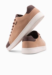 Hnědé plátěné tenisky s kulatou špičkou, kontrastní hnědou koženou patou, bílou podrážkou a hnědými tkaničkami. Texturovaný svršek s viditelným šitím.