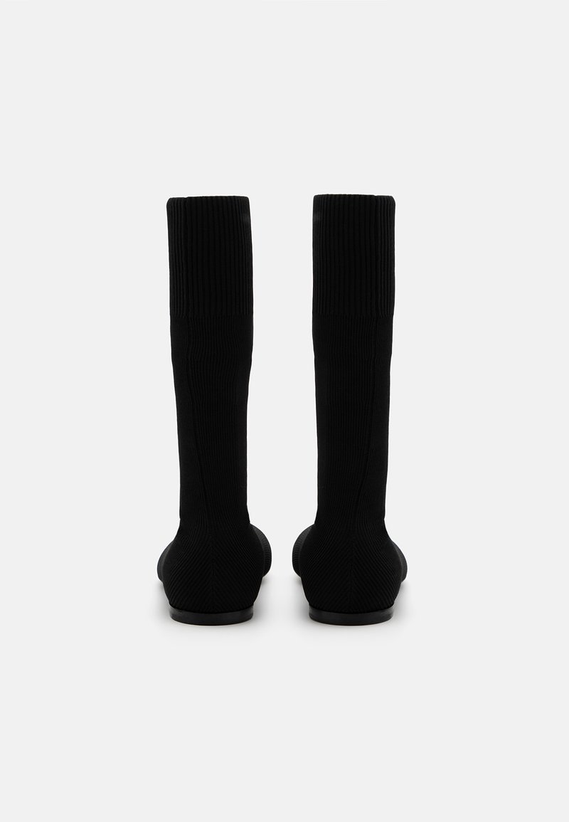 Svarta knähöga strumpor tillverkade av ribbat material med en slät textur, som har en åtsittande design och en minimalistisk form.