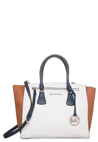 Bolso de Michael Kors con centro blanco, lados marrones, asas azul marino, un bolsillo frontal con cremallera, correa ajustable y charm redondo con el logo de MK.