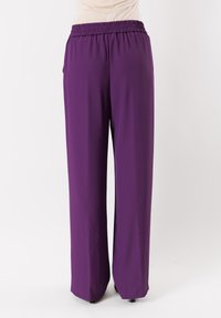 Pantaloni larghi viola con fascia elastica in vita. Realizzati in tessuto morbido e leggero; presentano un colore uniforme senza motivi o dettagli.